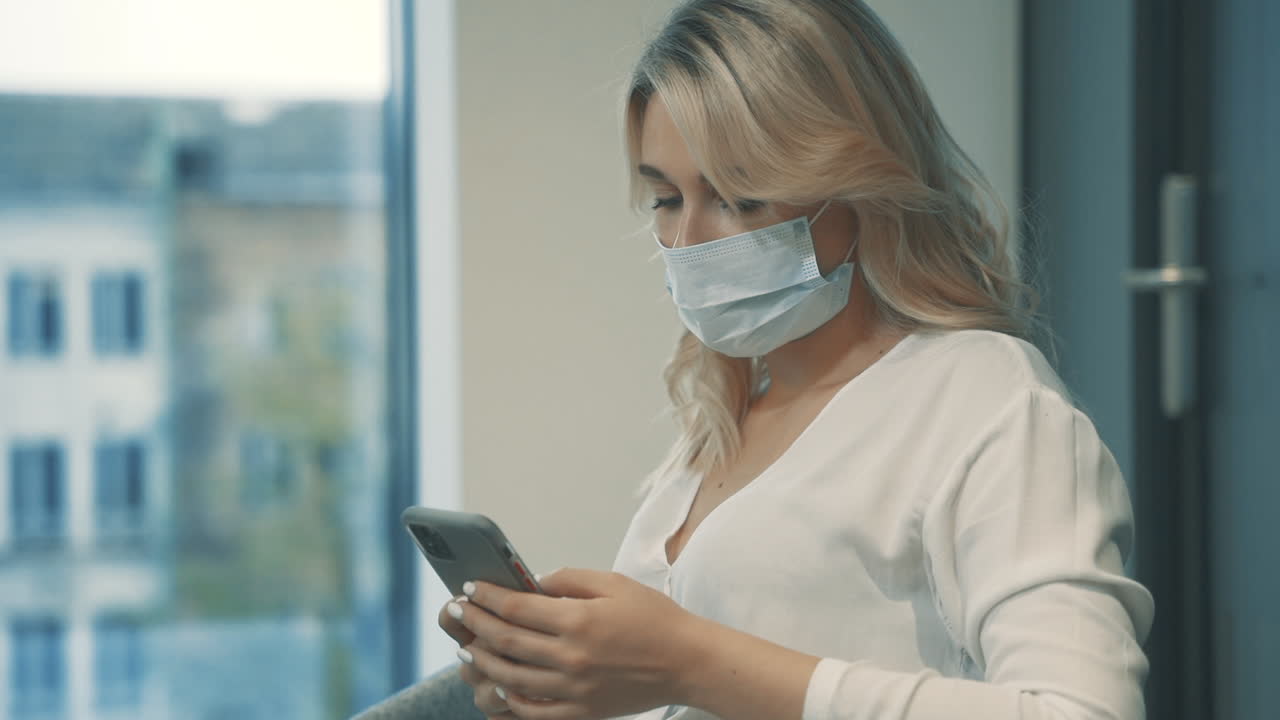 mujer de negocios con mascarilla enviando mensajes de negocios con un teléfono inteligente en la oficina