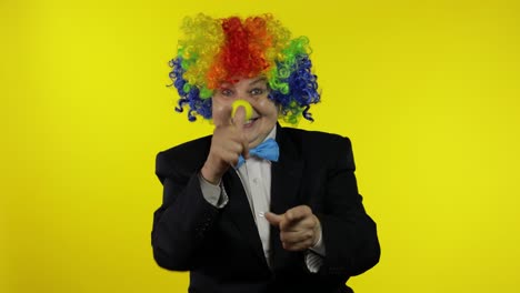 Senior-old-woman-clown-in-wig-smiling,-fool-around,-making-shot-signs-from-hands