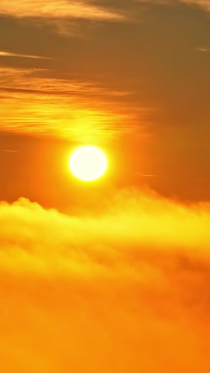 地平線上の劇的で色鮮やかな夕焼けの中、雲の後ろに沈んでいく輝く太陽の円盤。