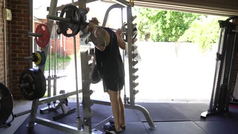 tattoo man muscles in home gym doing smith machine calf raise