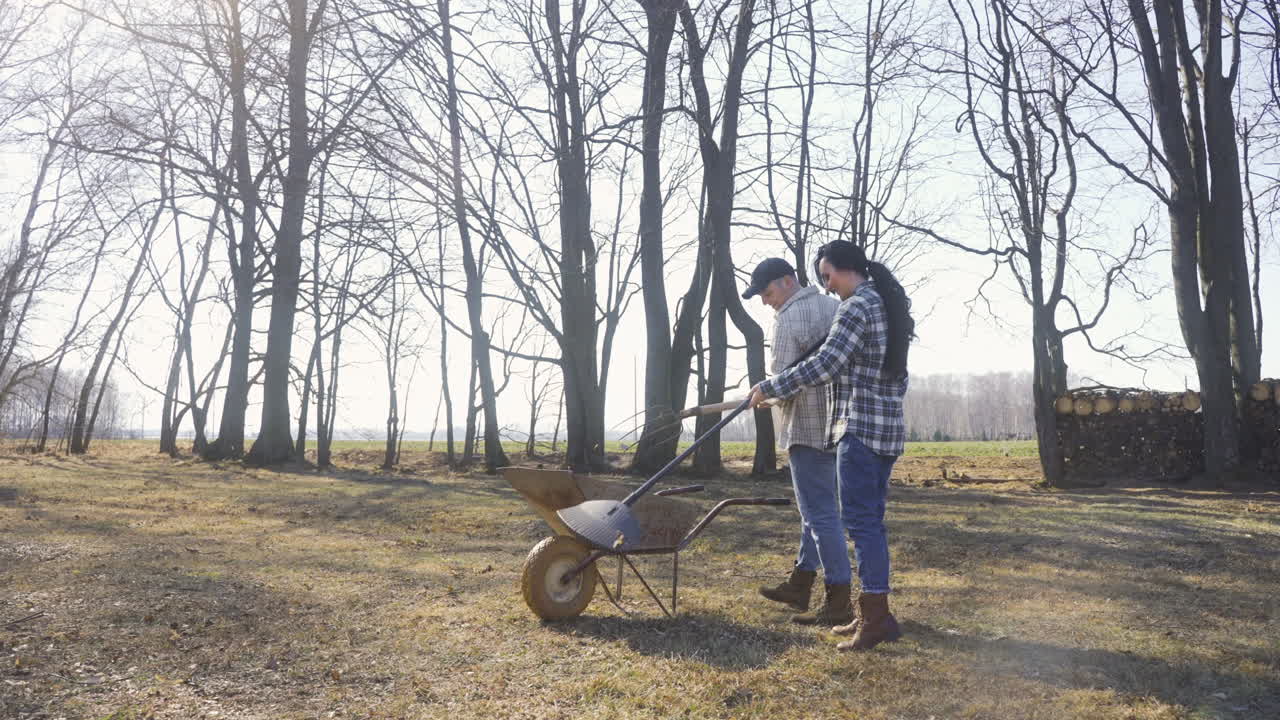 Distant view of caucasian couple removing weeds with a rake in the countryside