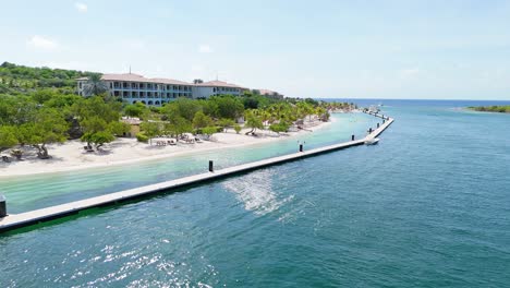 aerial dolly above shining caribbean water and tropical cabana rooms looking out at sea by santa barbara beach