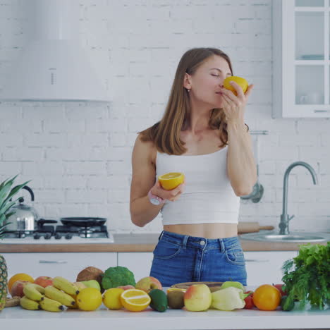 happy young woman enjoys organic fruit. beautiful woman with oranges in the kitchen on the background of many fresh vegetables and fruit.