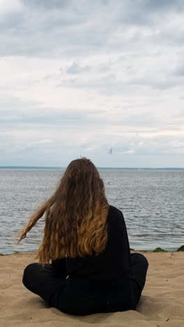 chica sentada en la playa contemplando el océano