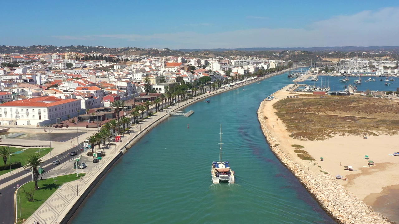 Vista aerea di un catamarano che naviga verso la marina con la città di Lagos in una giornata di sole in Portogallo