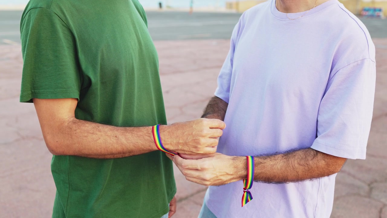 Uomo che allaccia un braccialetto arcobaleno Pride al polso del partner