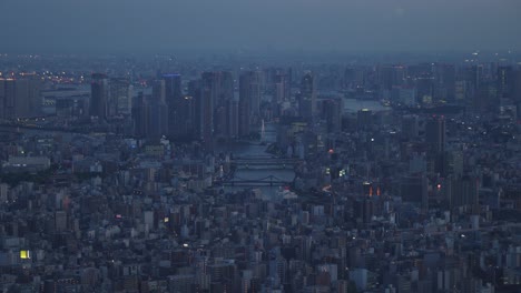 Handheld-general-view-of-the-buildings-and-overdeveloped-infrastructure-of-the-city-or-neighborhood-of-Koto,-Sumida-River-and-Kiyosu-bashi-bridge,-Tokyo-metropolis-at-blue-hour,-Japan