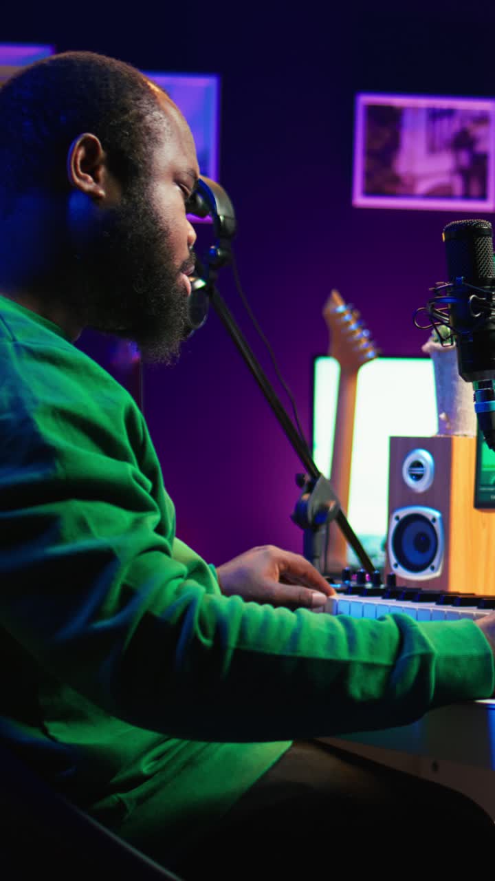 Afroamerikansk mand spiller keyboard og synger i musikstudie i hjemmet