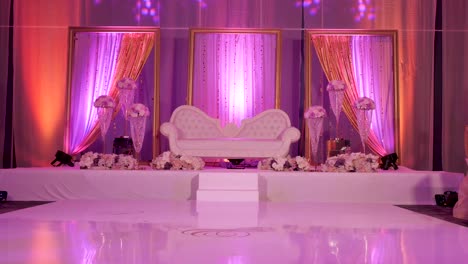 a forward moving shot of a love seat place on a stage for a wedding reception