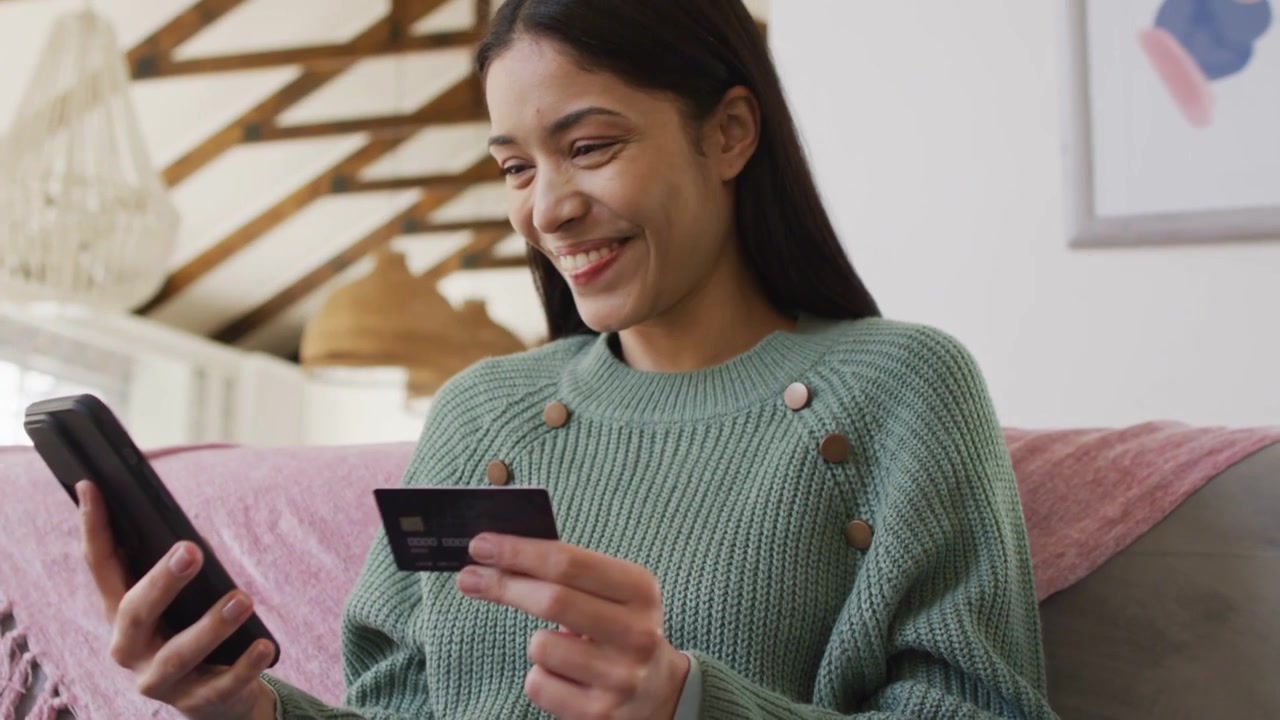 Mujer tocando el teléfono con una tarjeta para comprar en un loft, lo que provoca una avalancha de corazones financieros que luego se disipan para revelar una sonrisa.