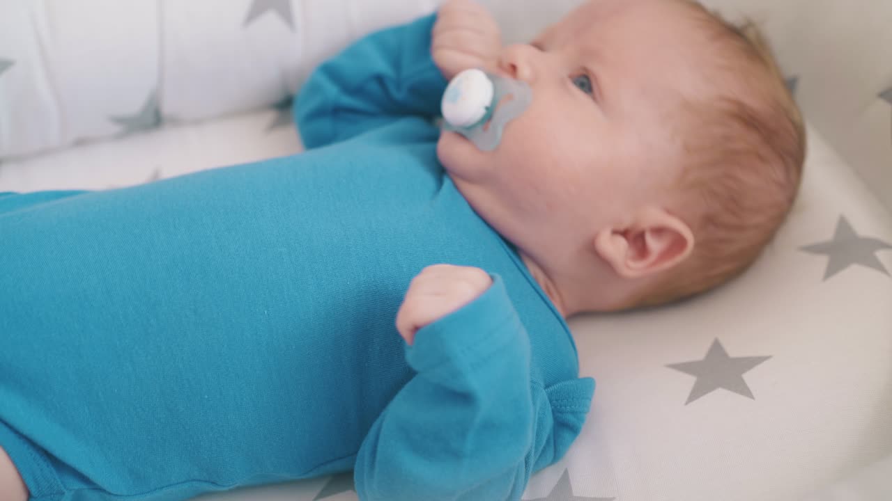 worried little baby sucks dummy resting in cocoon at home