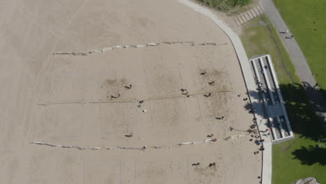 Drone-top-down-view-of-young-people-playing-beach-volleyball