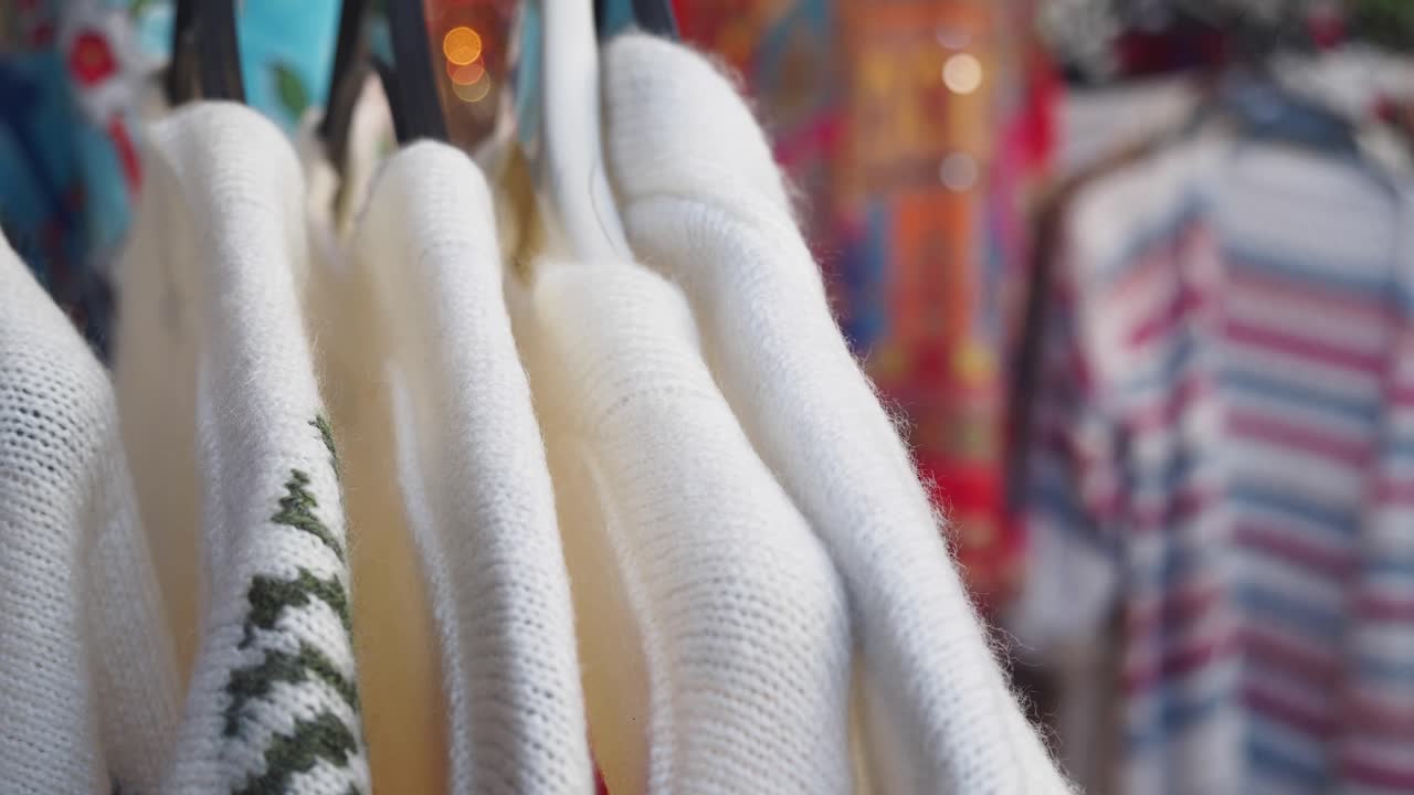 Close-up of White Knit Sweaters on Hangers