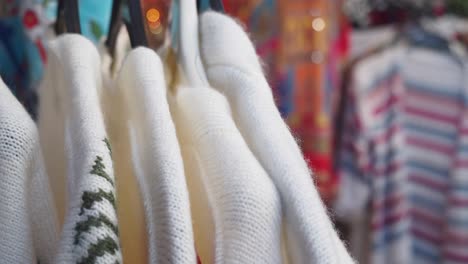 close-up of white knit sweaters on hangers