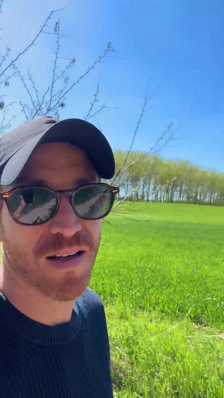 Male travel vlogger walking outdoors in a sunny wooded area. talking to the camera. explaining and creating content. Vertical UGC-style iPhone footage of a guy. making a story or a reel post. social