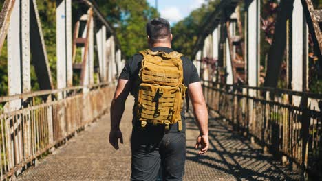 joven viajero caminando por el viejo puente oxidado al aire libre en un hermoso día soleado de verano