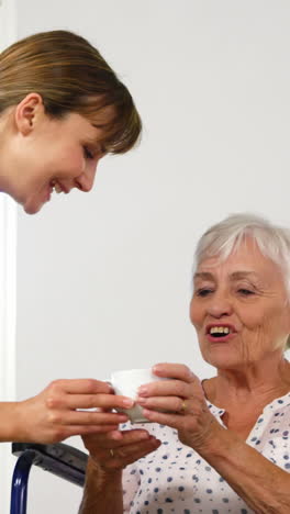 nurse giving a cup to mature woman