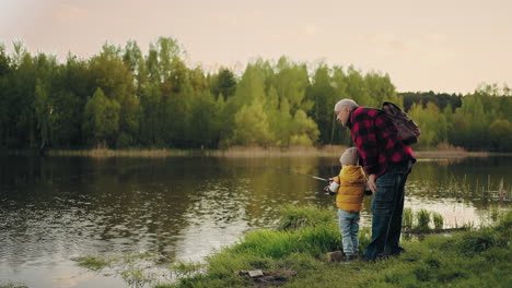 fishing on beautiful shore of forest lake little boy and grandfather are catching fish