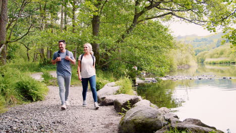 slow motion shot of young couple hiking along path by river in uk lake district