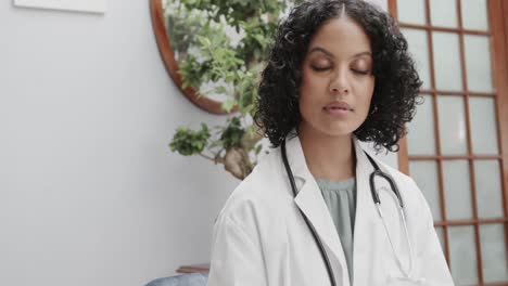 portrait of biracial female doctor wearing lab coat, holding clipboard, copy space, slow motion