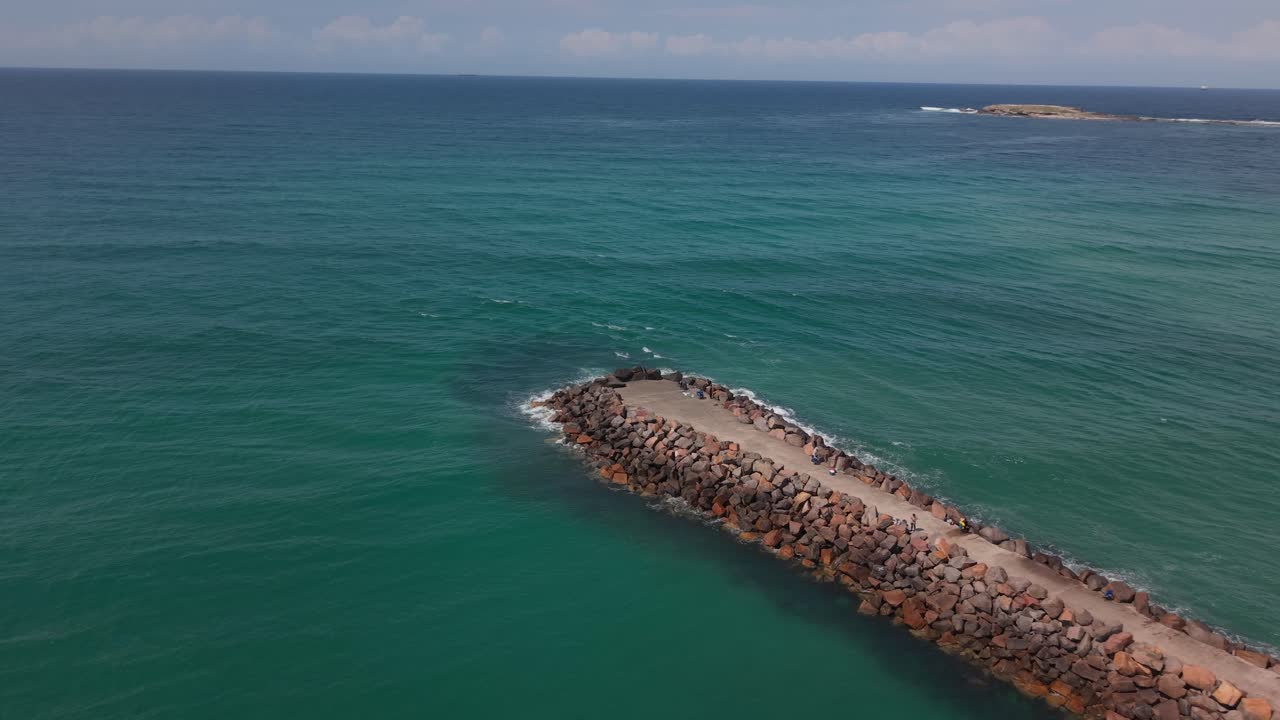 Ocean breakwall surrounded by deep green water, sunny conditions
