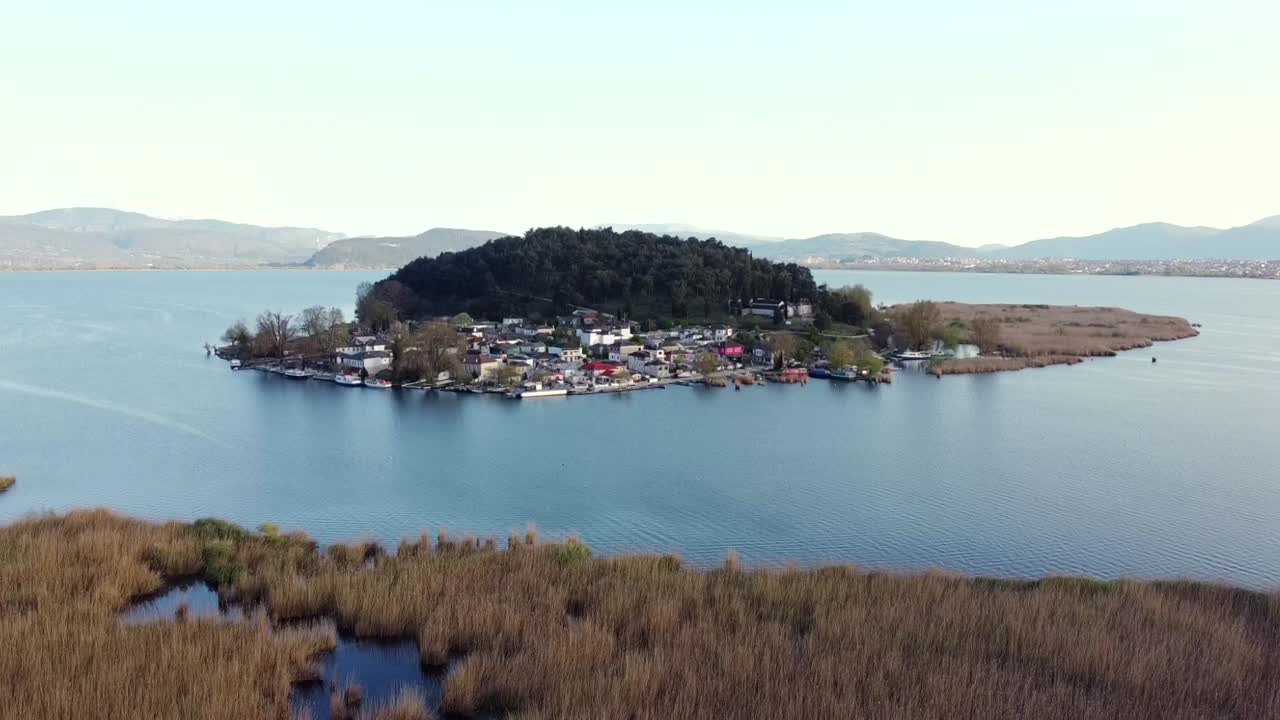 Ripresa panoramica con drone della storica Isola di Ioannina, una delle poche isole lacustri abitate in Europa. Vista dell'insediamento tradizionale e della vegetazione lussureggiante circondata da acque calme in Grecia.