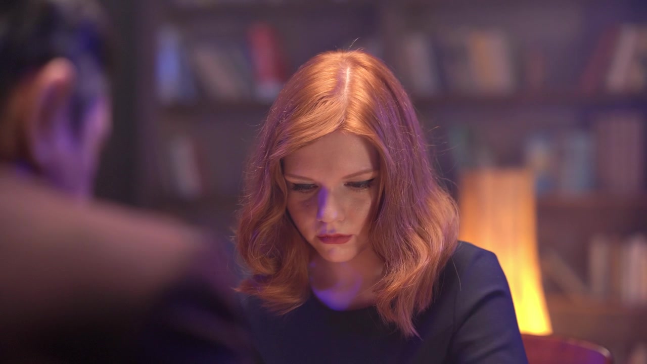 Focused Red-Haired Woman Playing a Board Game in a Dim Room