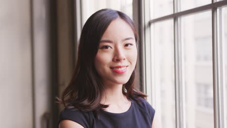 chinese businesswoman turns and smiles to camera, close up