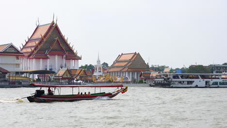 longboat travels past temple on bangkok river