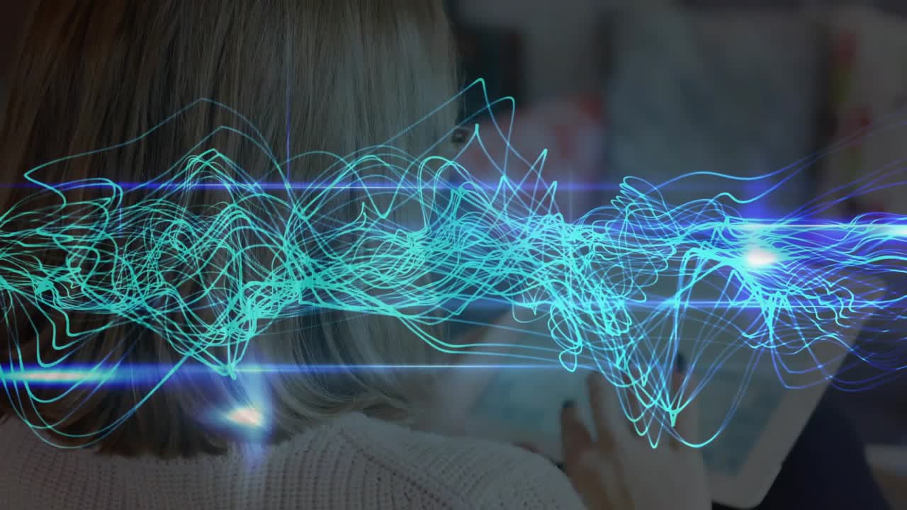 Man tapping tablet on couch, causing teal blue waveforms shifting real time for tech demonstration