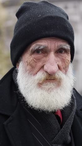portrait of an elderly man with a white beard wearing a winter hat