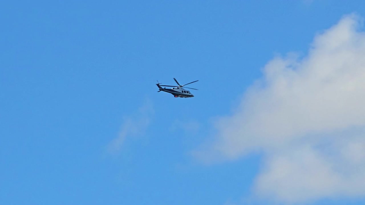日中、澄み切った真っ青な空を飛ぶ暗いヘリコプター。雲一つ見えず、十分なネガティブスペースがある中で、航空輸送が活動している様子を捉えたワイドショット。