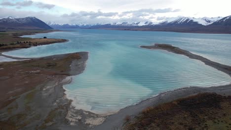 lake tekapo with snow-covered mountain peaks in the background in south island, new zealand. - aerial shot