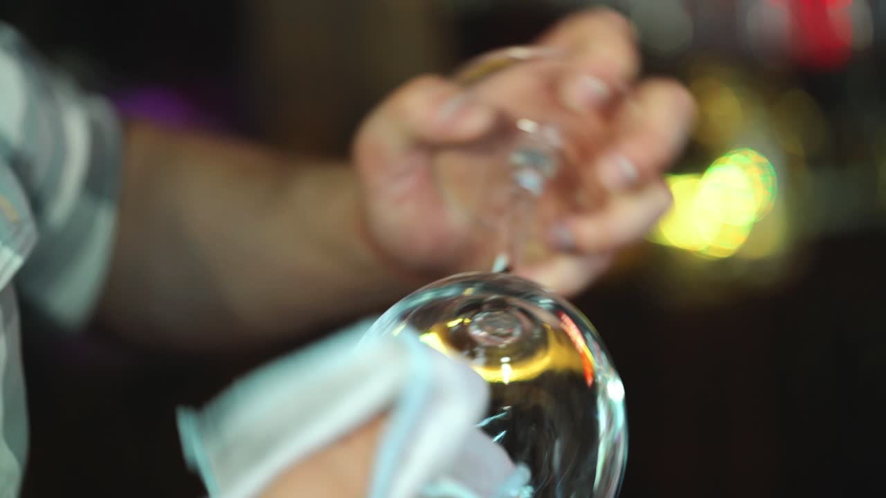 Bartender cleans the glass. Handsome bartender polishes a glass of wine glasses. Close up.
