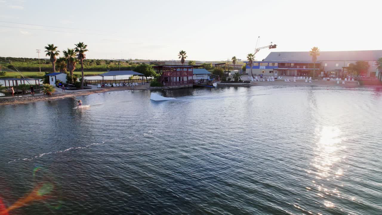 person wakeboarding going over a kicker doing tricks in the water Aerial view