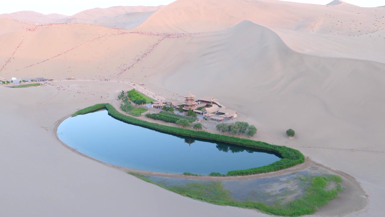 Filmato Aereo con Drone della Sorgente della Luna Crescente, Oasi del Deserto del Monte Mingsha al Tramonto, Dunhuang Gansu Cina. Ampia Ripresa Panoramica del Lago Crescente di Dunhuang Circondato da Gigantesche Dune di Sabbia, Antico Cinese