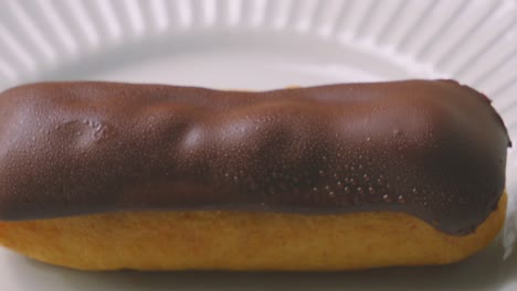 overhead view of delicious eclair topped with smooth milk chocolate and puff pastry filled with indulgent whipped cream. traditional french dessert ready to eat and enjoy. food photography.