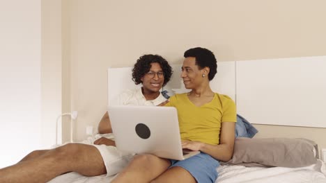 gay couple using laptop in bed