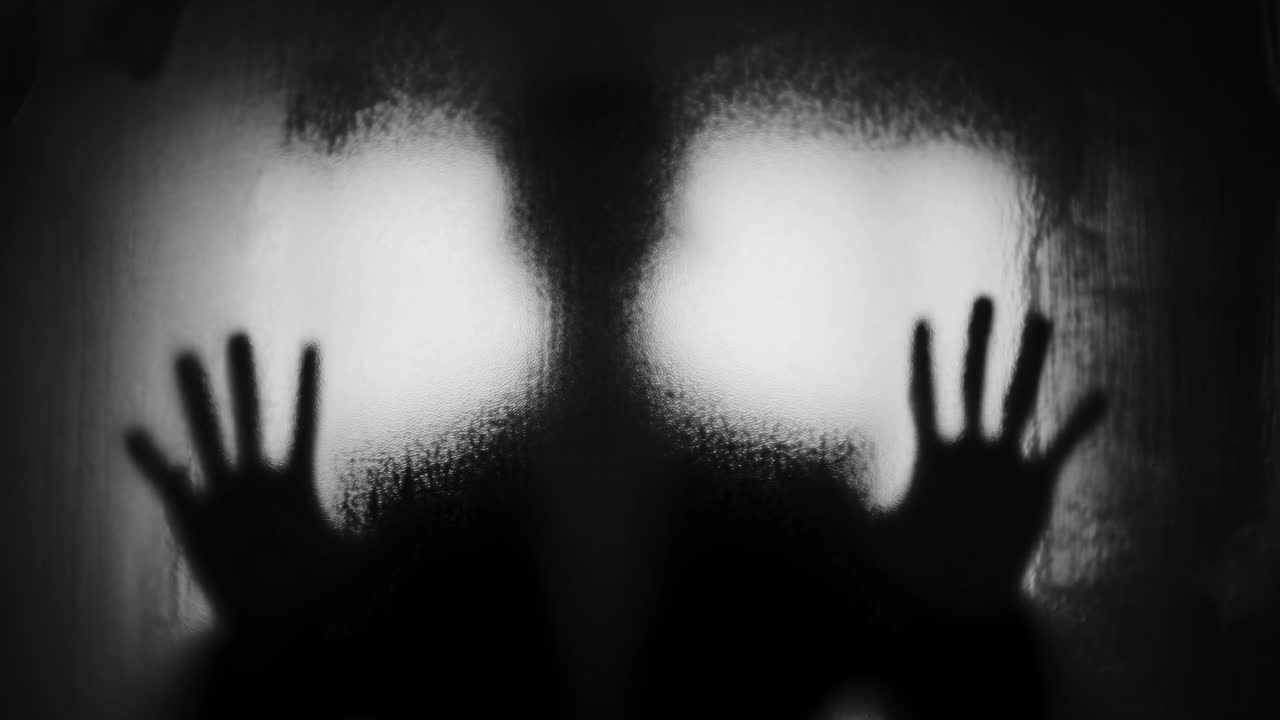 Silhouette of Person's Hands Pressing Against Frosted Glass