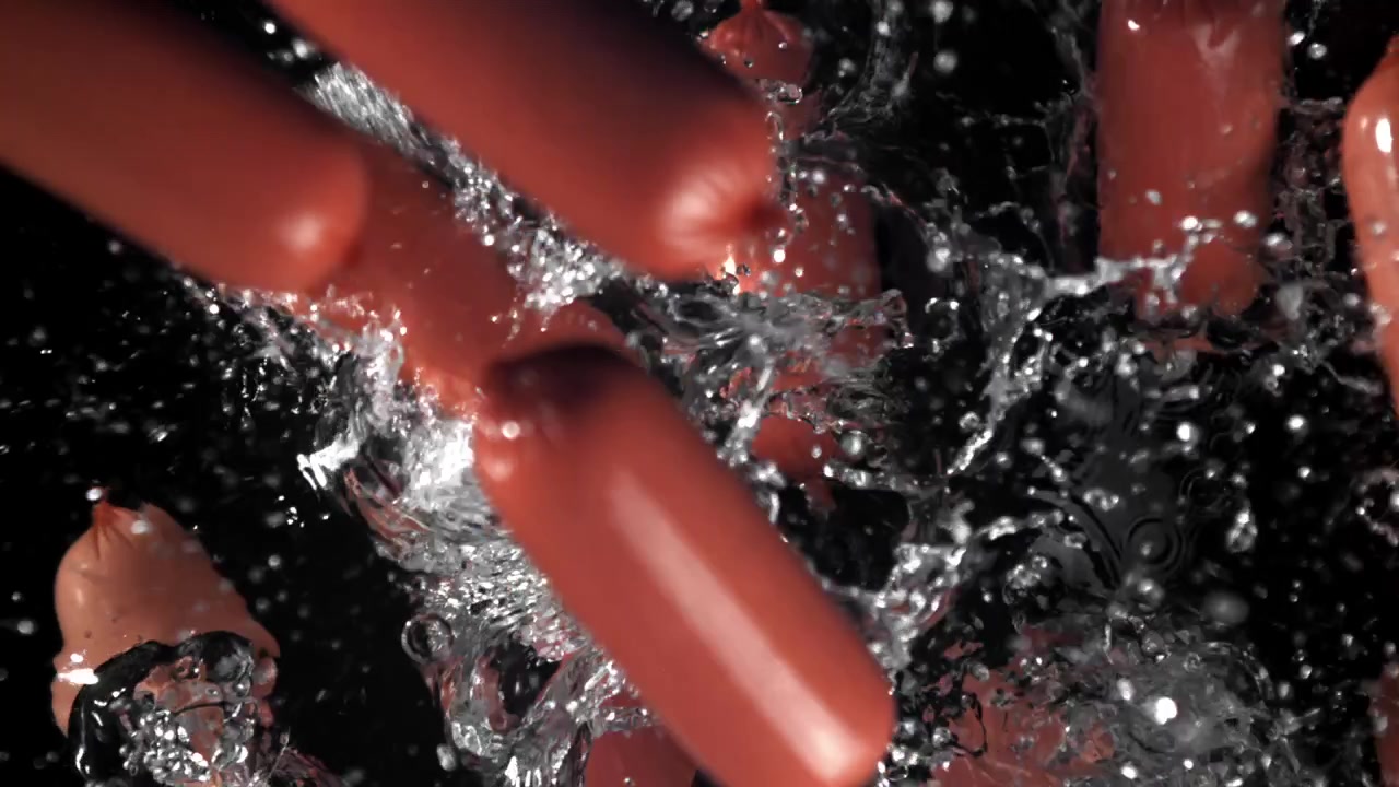 Salsicce rosse che cadono nell'acqua con schizzi al rallentatore