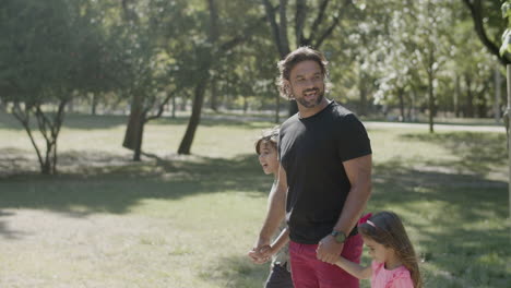 side view of man with disability strolling with kids in park