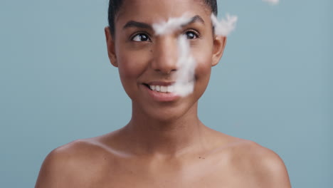 slow motion beauty portrait beautiful woman smiling feathers falling on healthy skin touching bare shoulders enjoying luxury skincare gently caressing body in blue background