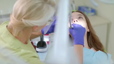 dentist making professional teeth cleaning of female patient in dental clinic