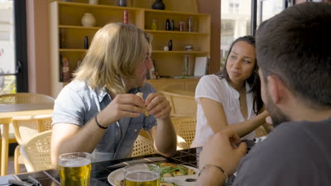 grupo de amigos comiendo pizza sentados en una mesa de restaurante mientras hablan entre ellos