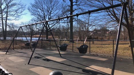 empty toddler swing set in park, winter time