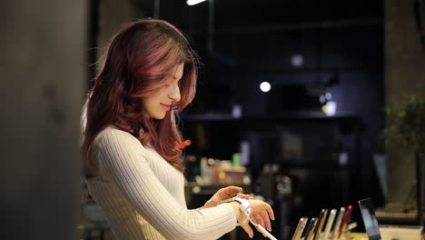 a young woman with wavy hair is looking at a smart watch in an electronics store. high quality 4k footage