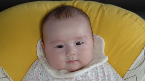 cute baby girl lying on soft cushion looking and smiling at camera