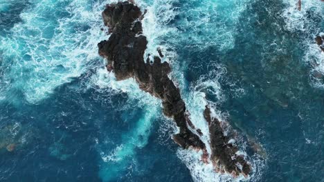 slow motion drone video in porto moniz madeira where waves hits a rock and splashes