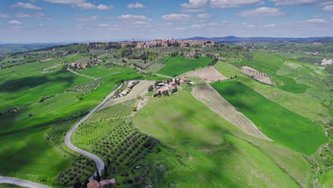 Ciudad-De-Pienza-Por-Plantaciones-De-Olivos-En-Toscana,-Amplia-Antena-Delantera