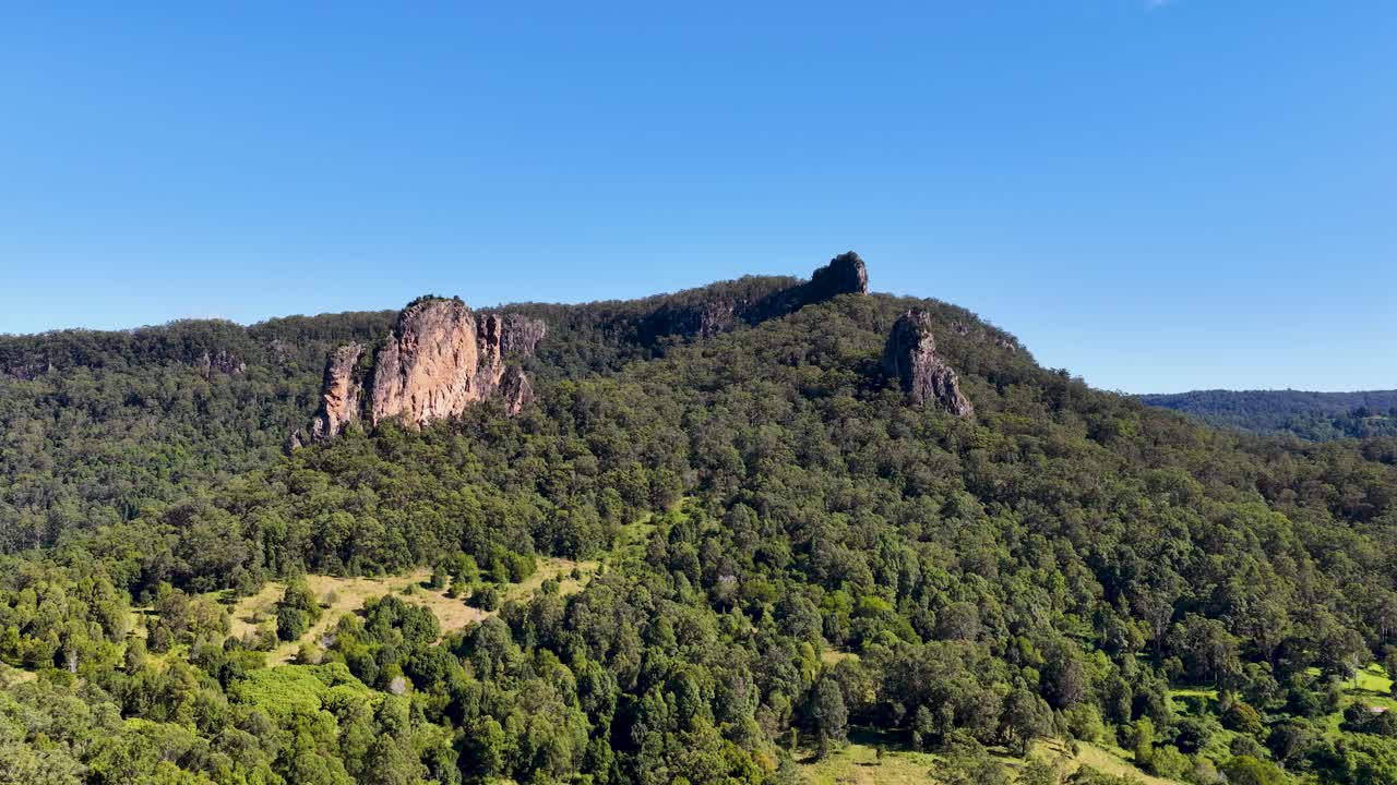 Aerial footage of Nimbin Rocks, showcasing lush greenery and rocky formations under clear blue skies